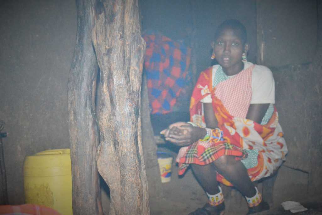 A mother sitting in the dark when we enter Maasai traditional house